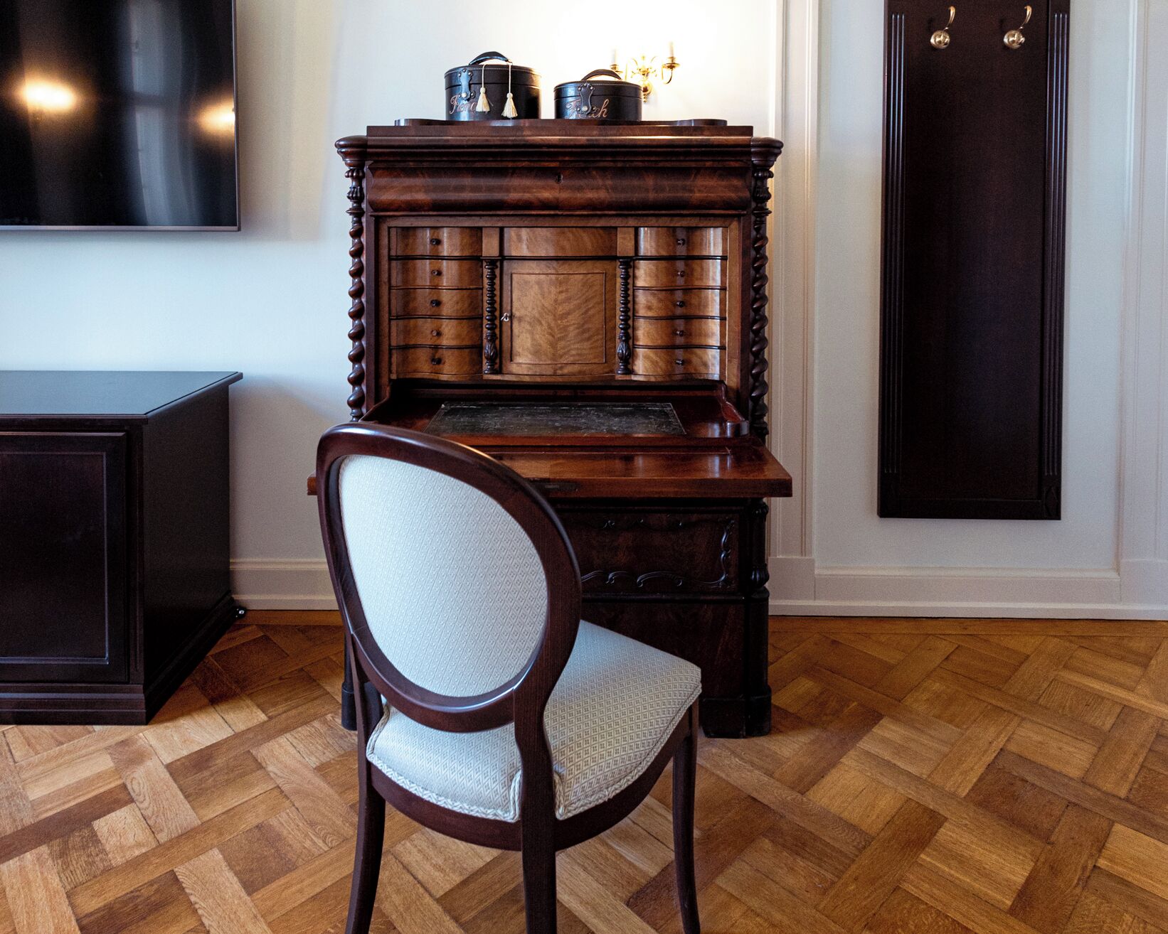 A wooden cabinet with multiple drawers and a chair in front.