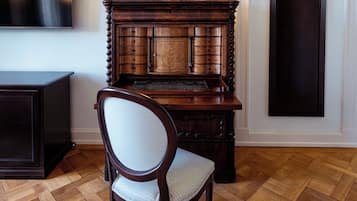 Een houten kast met meerdere lades en een stoel ervoor.