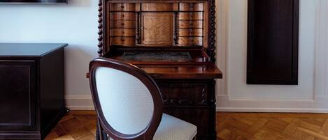 A wooden cabinet with multiple drawers and a chair in front.