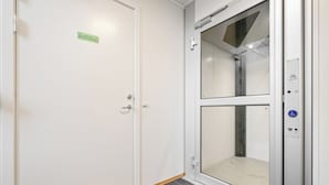 Un ascenseur propre et moderne, doté d’une porte en verre et d’un panneau indiquant un espace d’attente.