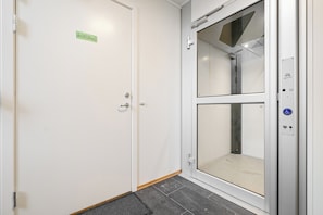 Een schone, moderne lift met een glazen deur en een bordje dat een wachtruimte aangeeft.