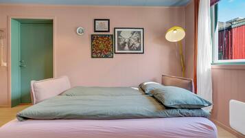 Un dormitorio con cama, almohadas, lámpara de noche y decoración en la pared.