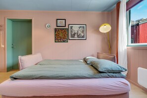 Une chambre à coucher avec un lit, des oreillers, une lampe de chevet et des œuvres d’art murales.
