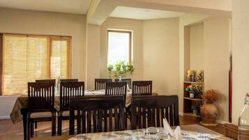 A dining area with a round table, six chairs, and a vase with flowers.