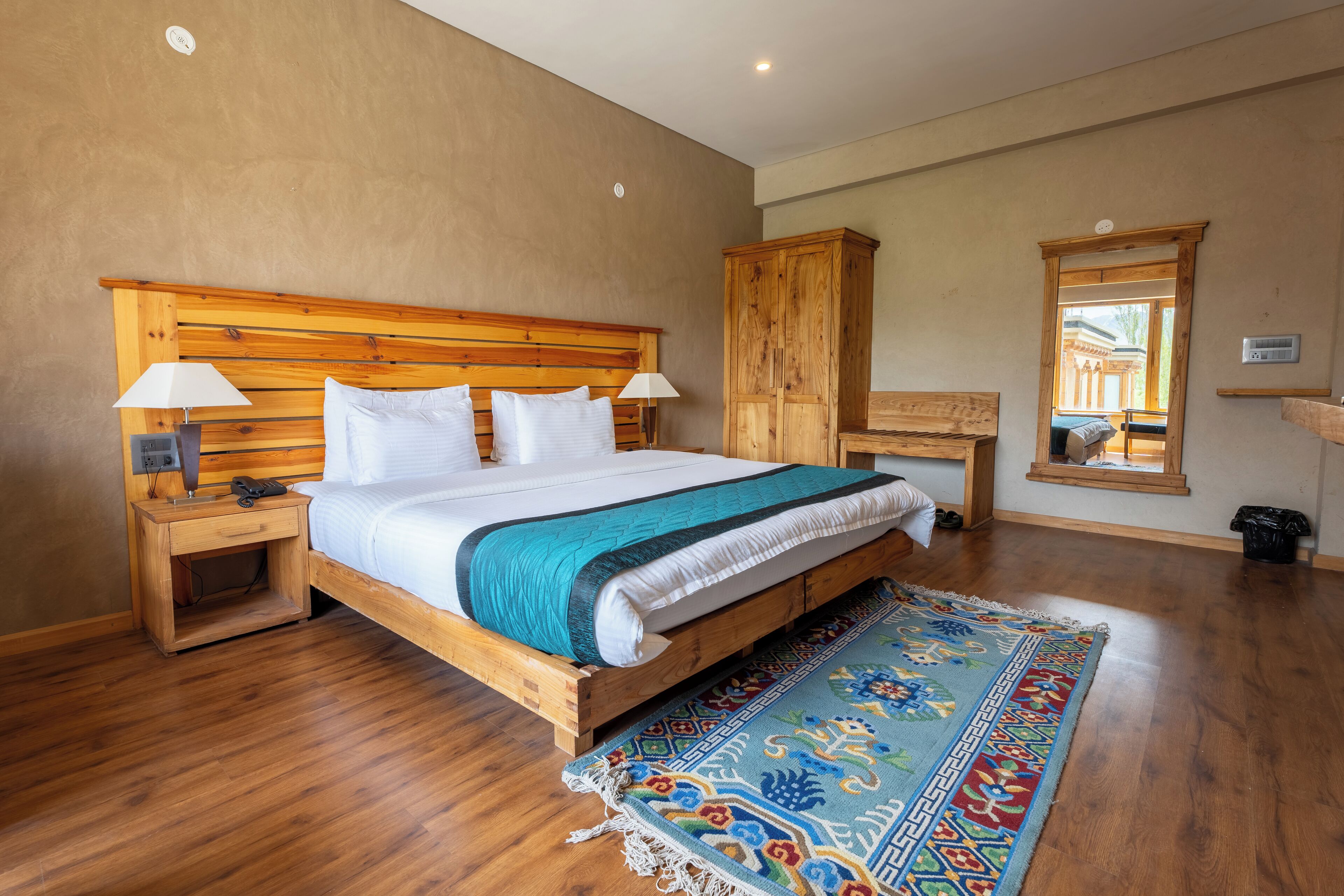 A bedroom with a wooden bed, nightstands, a wooden wardrobe, and a large mirror.