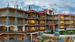 Un hotel de varios pisos con fachadas de piedra, balcones y zonas de estar al aire libre.