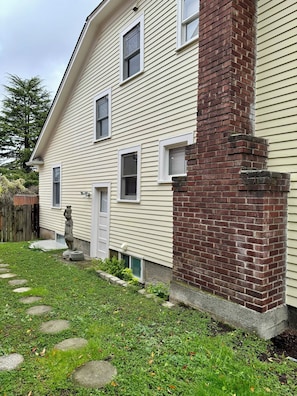 A two-story house with a brick chimney, a small front yard with stepping stones, and a wooden fence. - Spacious 4-bedroom house in awesome Seattle with WiFi, AC (Seattle)