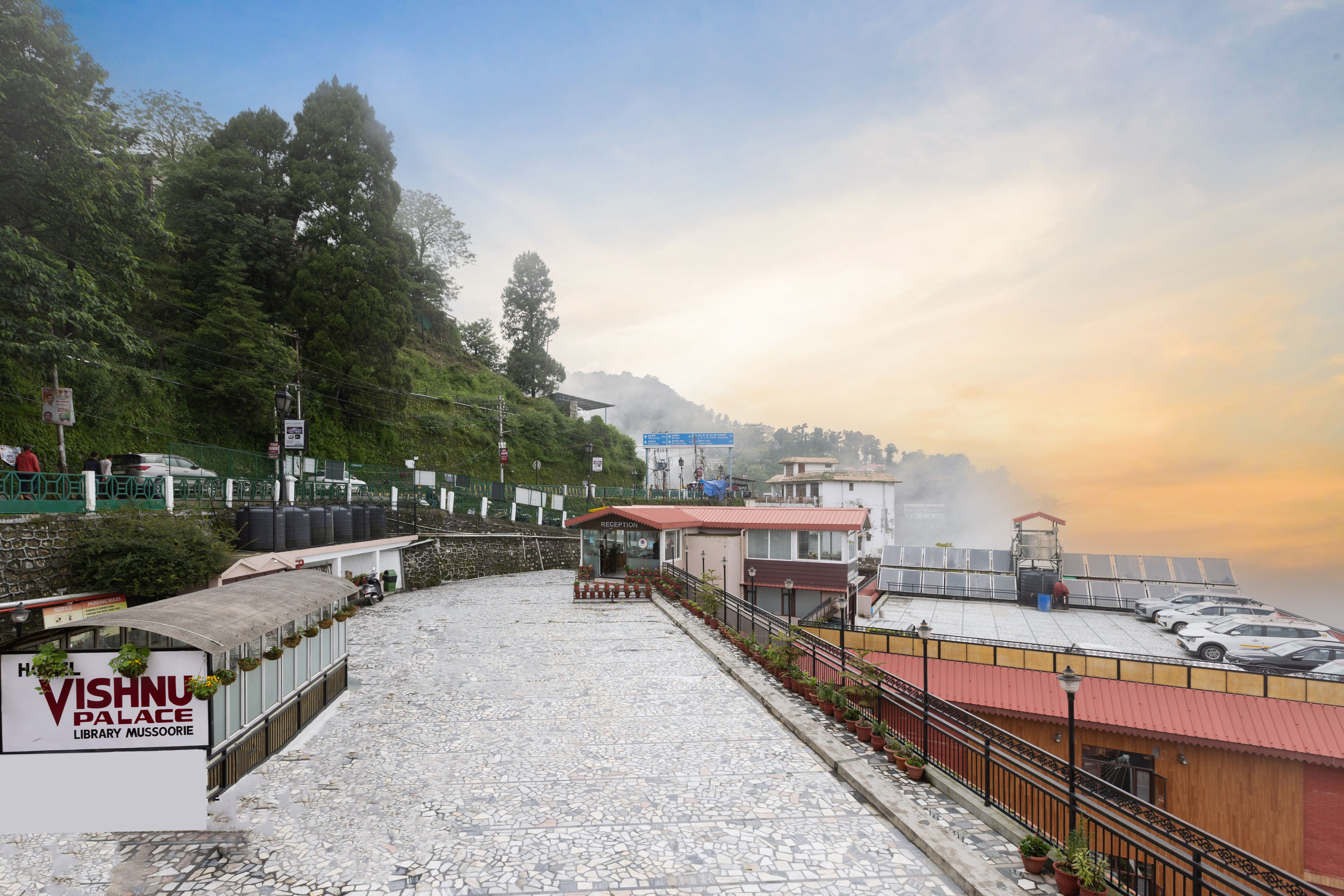 A paved pathway leading to a reception area with a sign for the Vishnu Palace Library.