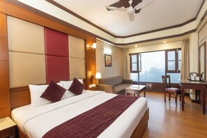 Habitación de hotel con una cama grande, un escritorio, un sofá y vistas al exterior.