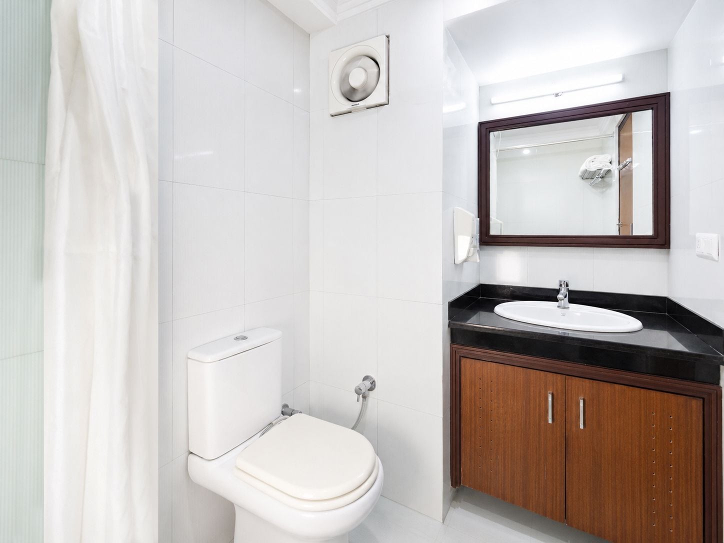 A modern bathroom with a toilet, sink, and mirror.