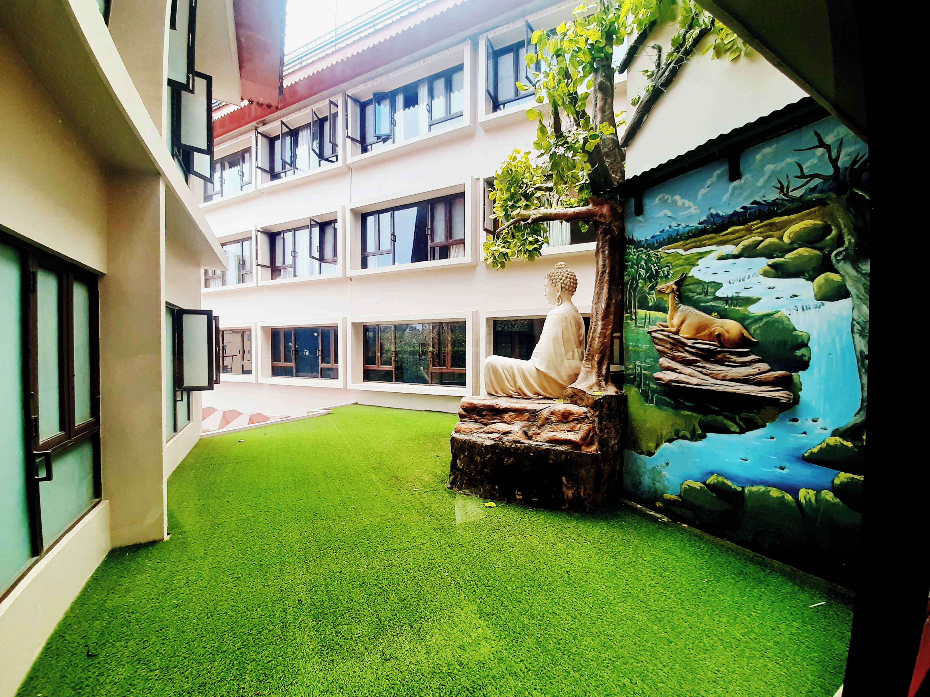 A building with multiple floors, a statue of a seated figure, and a mural of a landscape with a waterfall and deer.