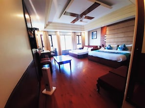 Una habitación de hotel con cama, sofá, escritorio y ventilador de techo.
