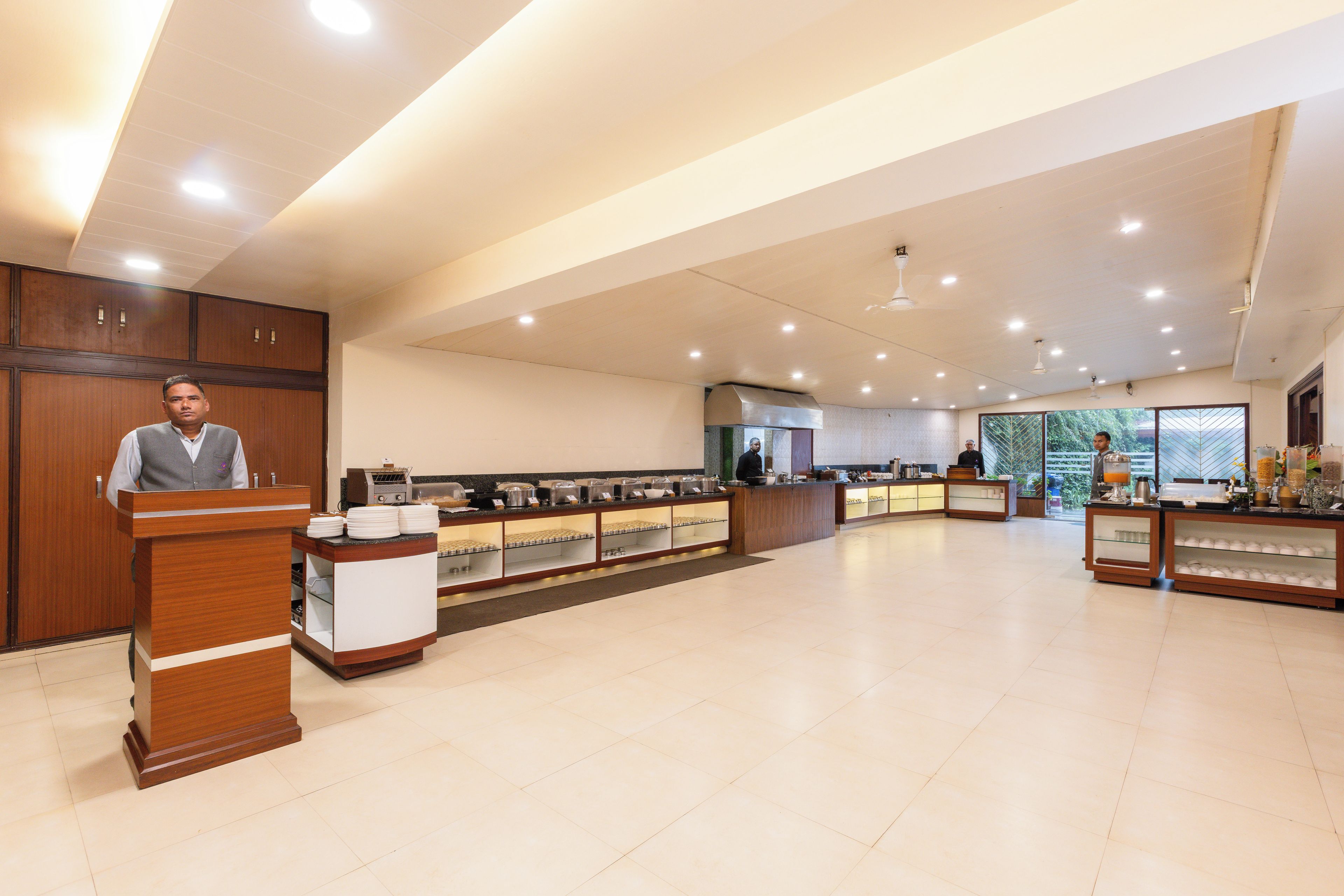 A hotel lobby with a reception desk, a buffet area, and a large window offering a view.