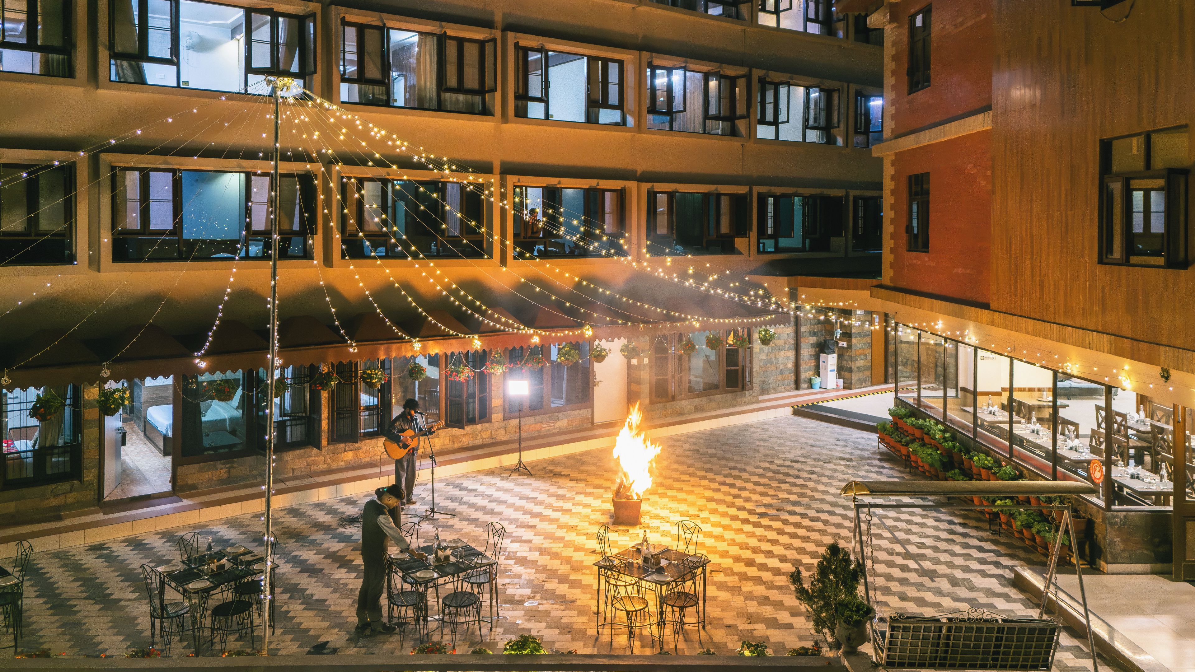 A courtyard with a fire feature, outdoor seating, and string lights.