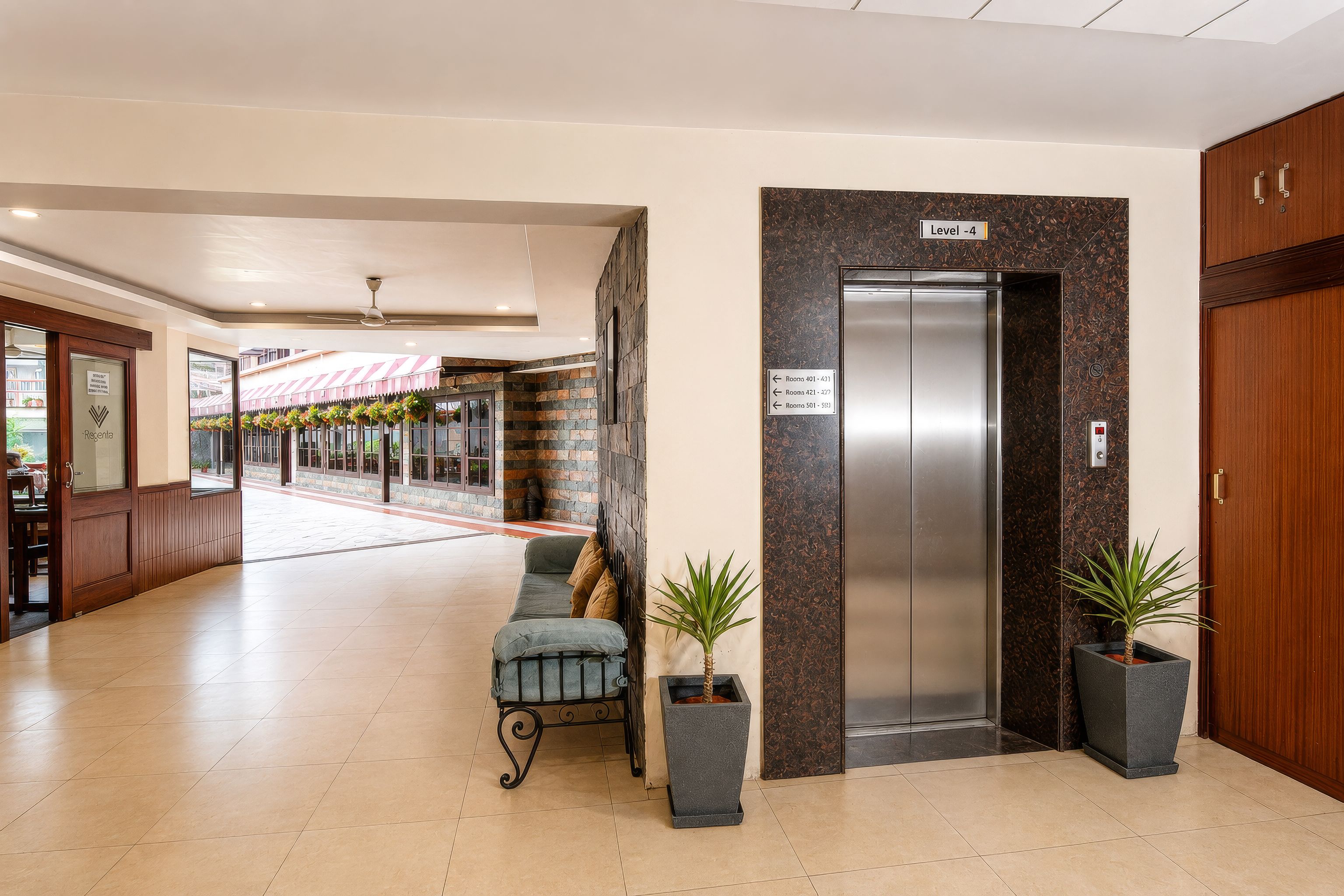 An indoor lobby with a reception desk, a seating area with a sofa, and an elevator.