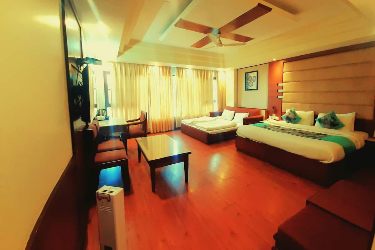 A hotel room with a large bed, a sofa, a desk, and a ceiling fan.