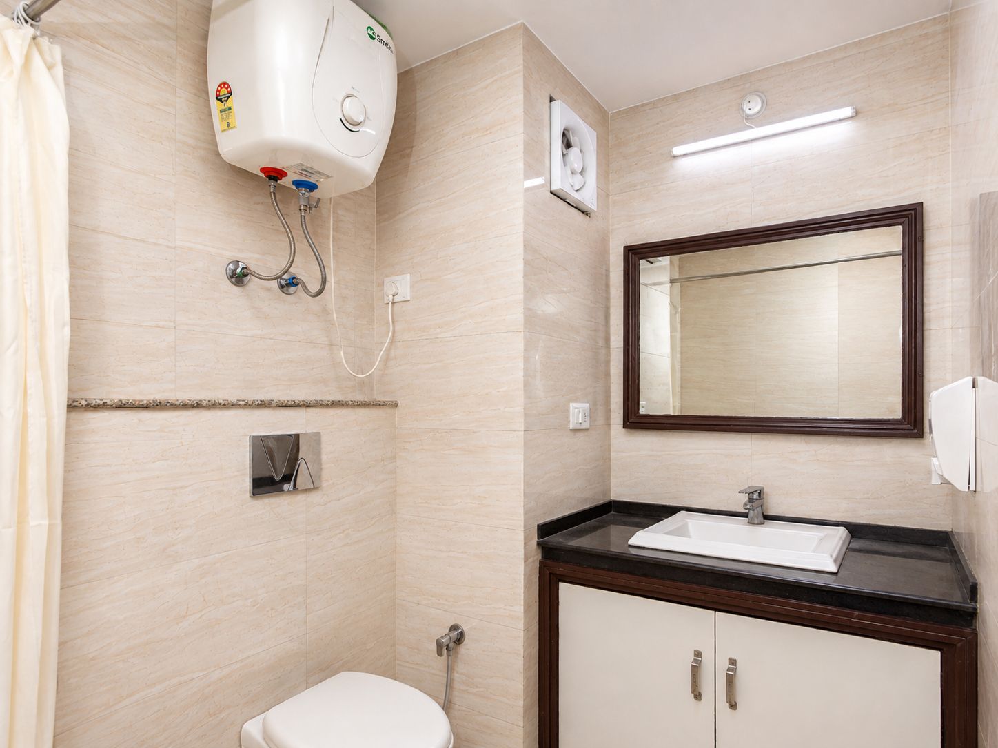 A bathroom with a toilet, a sink, a mirror, and a shower unit.
