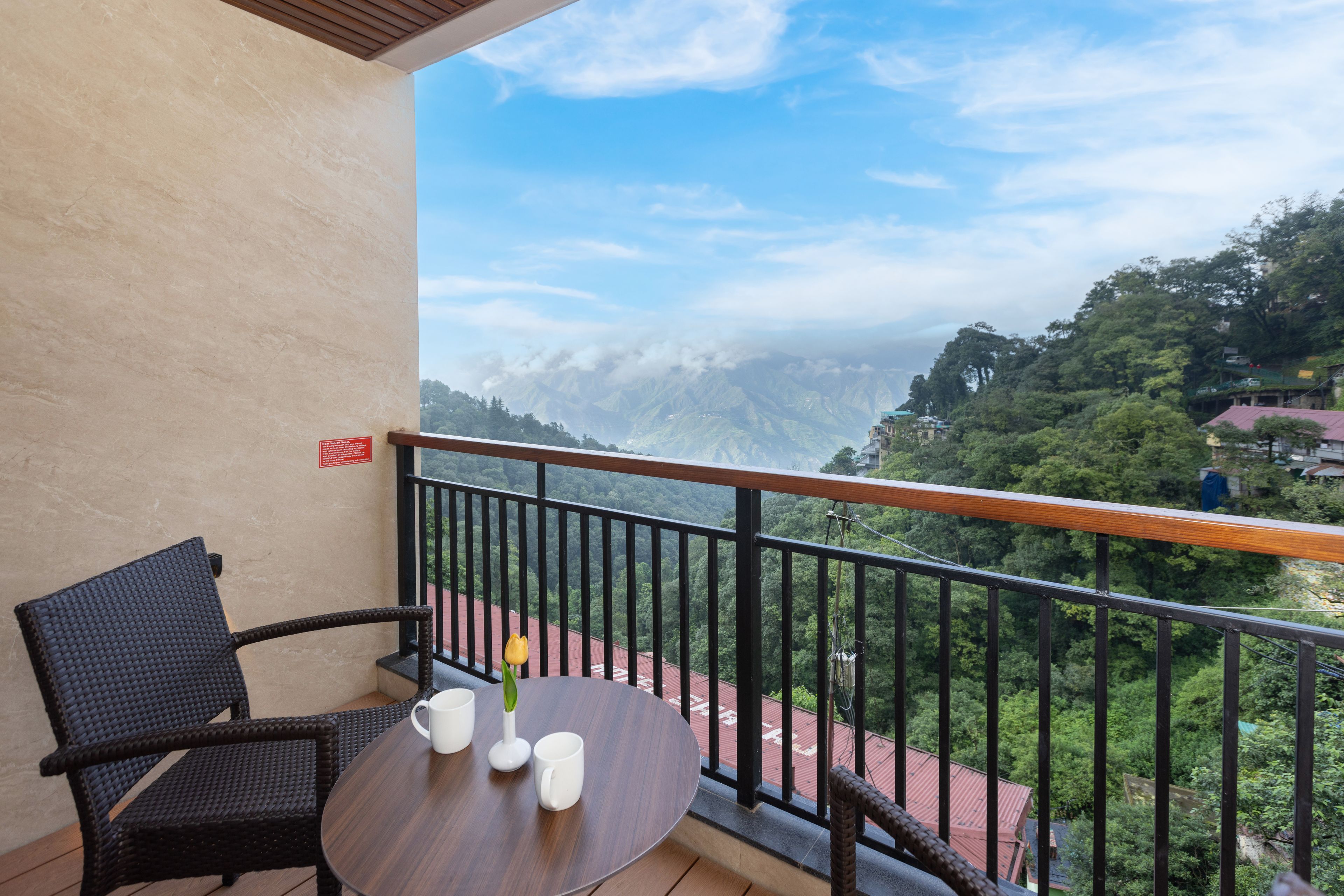 A balcony with a table and chairs, overlooking a mountainous landscape.