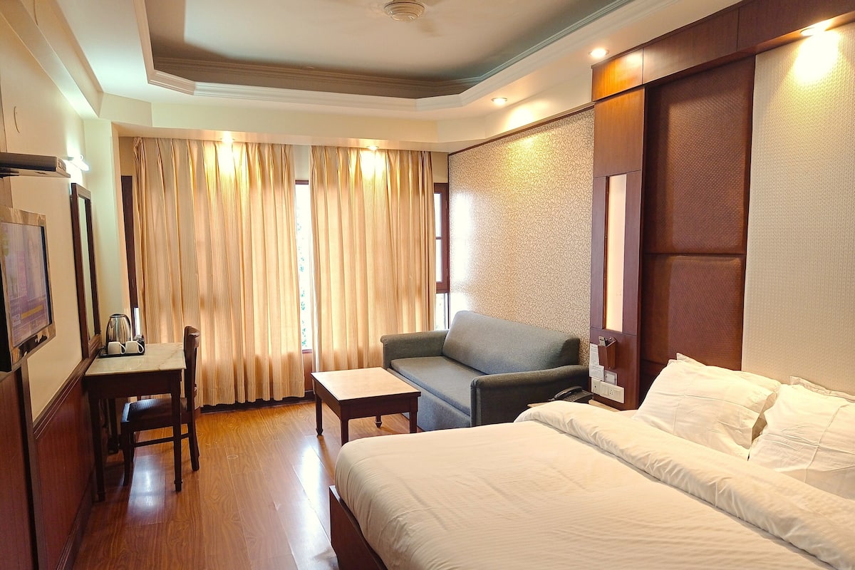 A hotel room with a bed, a sofa, a desk, and a chair.