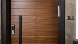 A wooden door with a keypad lock and a number "153" on the wall beside it.