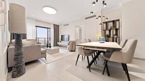 A modern living room with a dining area, a sofa, a TV, and a large window.