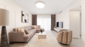 A modern living room with a sofa, coffee table, and a patterned ottoman.