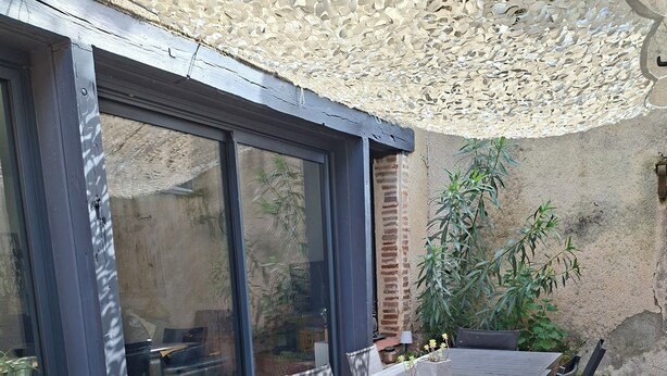 Eine Terrasse mit Tisch und Stühlen, einer Pergola und Blick auf den Garten.
