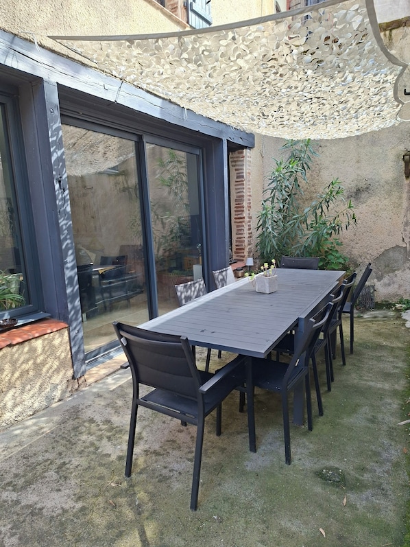 Une terrasse avec une table et des chaises, une pergola et une vue sur le jardin.