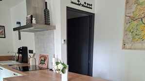 Eine moderne Küche mit einer großen Kochinsel, Edelstahl-Barhocker, einer schwarzen Tür und einer Karte an der Wand.