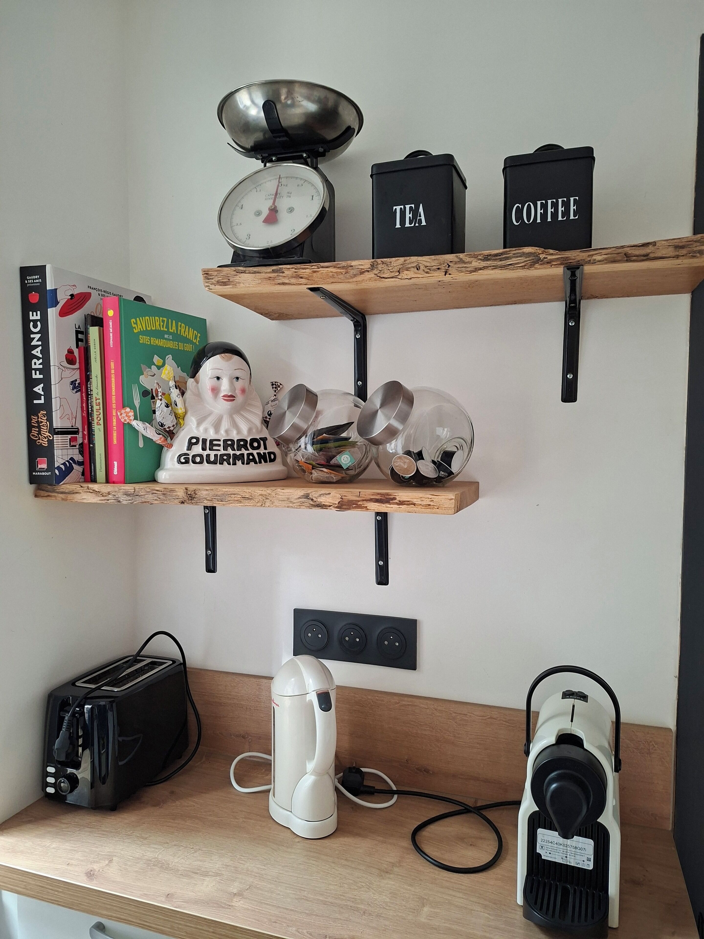 Eine Küche mit Waage, Tee- und Kaffeebehältern, Kochbuch, Schneebesen, Toaster und Staubsauger.