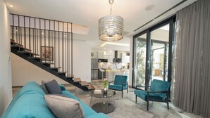 Ein modernes Wohnzimmer mit einem türkisfarbenen Sofa, einem Couchtisch und einer Treppe, die zu einer oberen Etage führt.