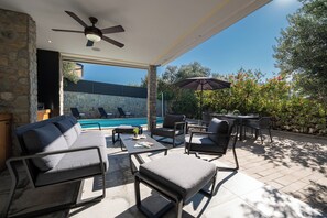 An outdoor patio with a pool, seating area, and a ceiling fan. - Villa Picholine (Novalja)