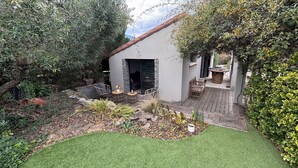 A patio area with a stone wall, outdoor seating, and a small garden. - Maison T2 Casa Alegria Peace and greenery in the heart of the Pyrénées-Orientales  (Joch)