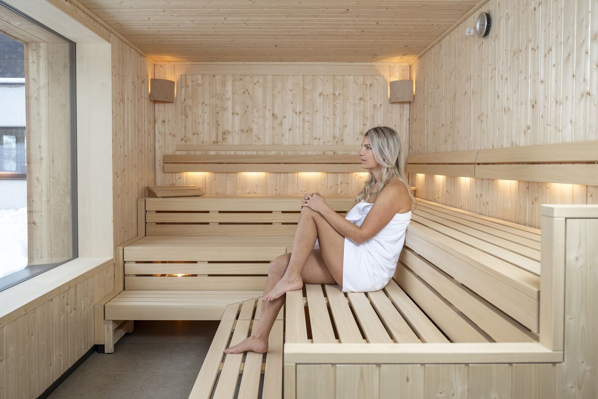Un sauna en bois, doté de bancs et d’une fenêtre donnant sur l’extérieur.