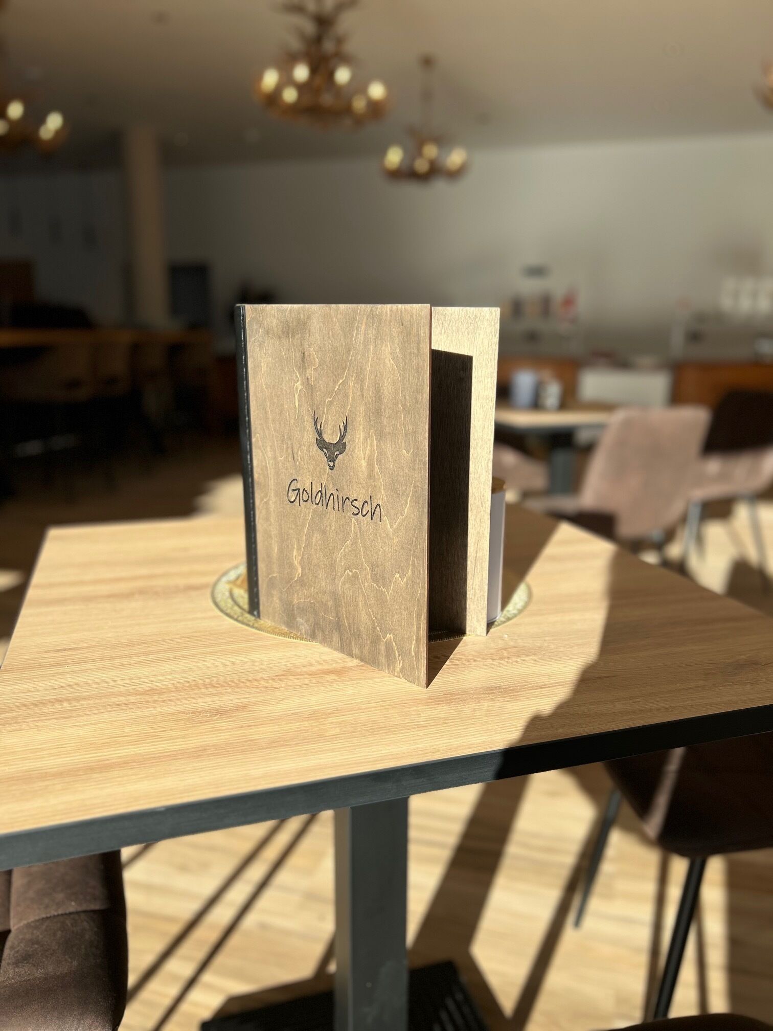 A wooden table with a box labeled "Goldhirsch" in a room with a modern interior.