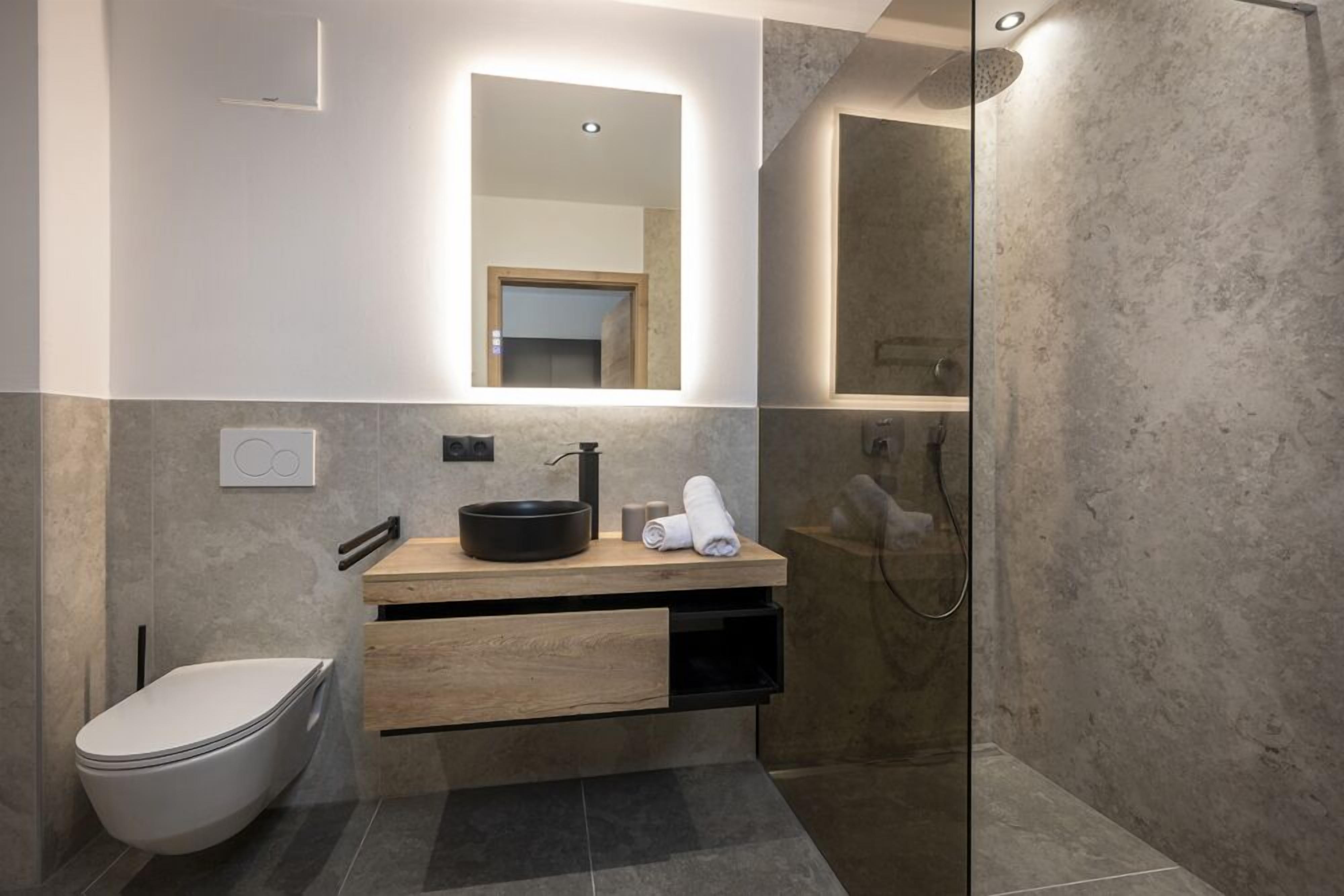 Een moderne badkamer met toilet, wastafel en douche.
