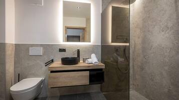 Een moderne badkamer met toilet, wastafel en douche.