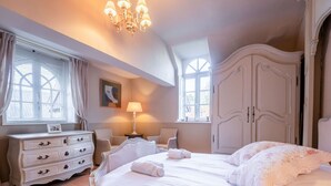 A bedroom with a large bed, a dresser, a lamp, and a wardrobe.