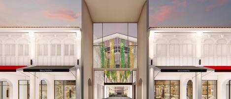 A modern building with a central atrium and glass facade, featuring storefronts labeled "BRANDING" on either side.