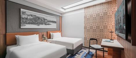 A hotel room with two beds, a desk, a chair, a TV, and a large window.