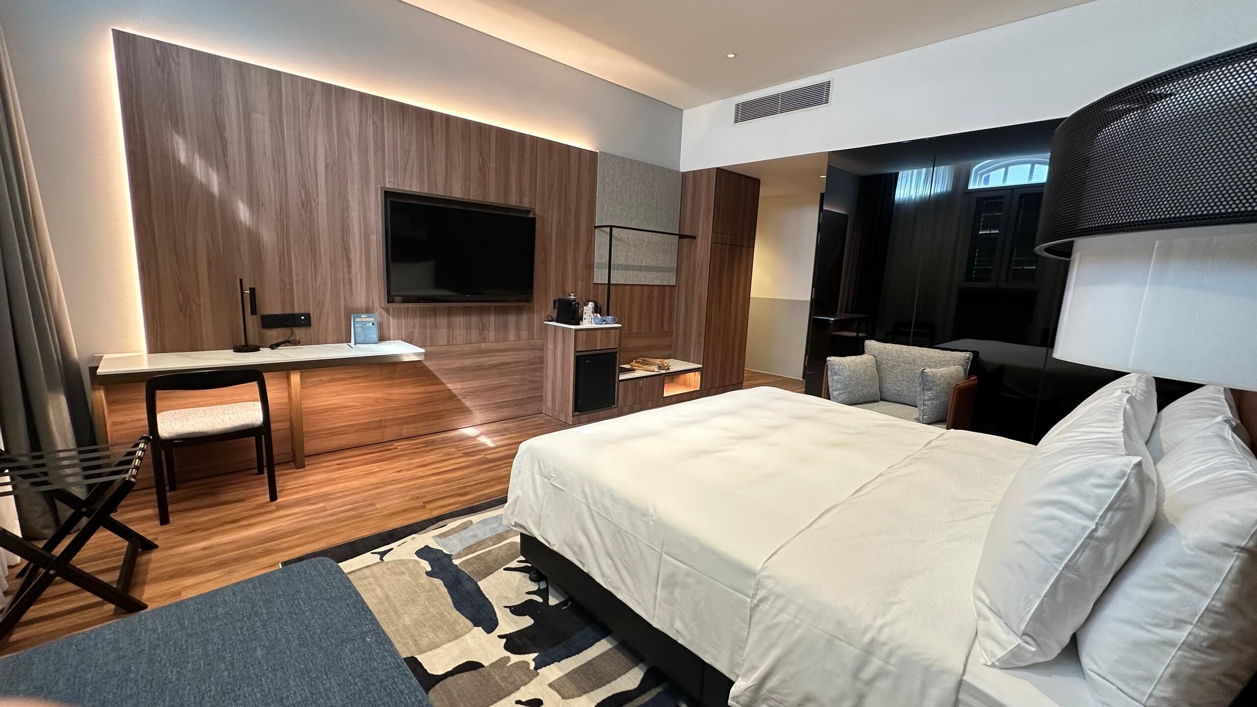 A modern hotel room with a bed, desk, and seating area.