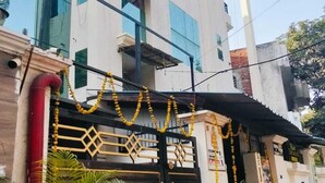 Um edifício moderno com portão preto, decorado com guirlandas amarelas, e rodeado por plantas em vasos.
