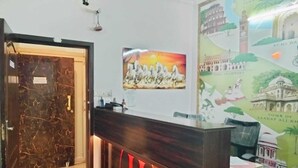 Bancada de recepção com porta de mármore, quadro com cavalos emoldurados e um mural retratando pontos turísticos.