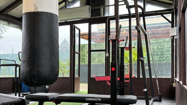 Un gimnasio con un saco de boxeo, banco de pesas y varios equipos de ejercicio.