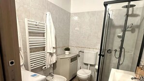 Un baño pequeño con inodoro, bidé y cabina de ducha.