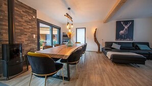 A modern living room with a dining area, featuring a fireplace, a sofa, and a large deer artwork on the wall. - 
Maéva's Chalet: Jacuzzi and Terrace. (Xonrupt-Longemer)