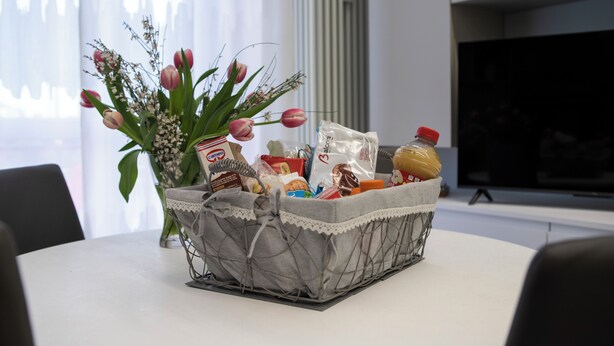 A table with a basket containing food items and a bouquet of flowers. - Magic Home Turin  (Torino)