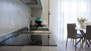 A modern kitchen with a built-in stove, a sink, and a dining area with a table and chairs. - Magic Home Turin  (Torino)