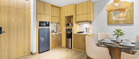 Une cuisine moderne avec des meubles en bois, un four encastré et un coin repas comprenant une table ronde et des chaises.