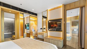 A modern hotel room with a large bed, a TV, a minibar, and a bathroom with a bathtub. - Moriya by Kozystay - Nusa Dua (Nusa Dua)